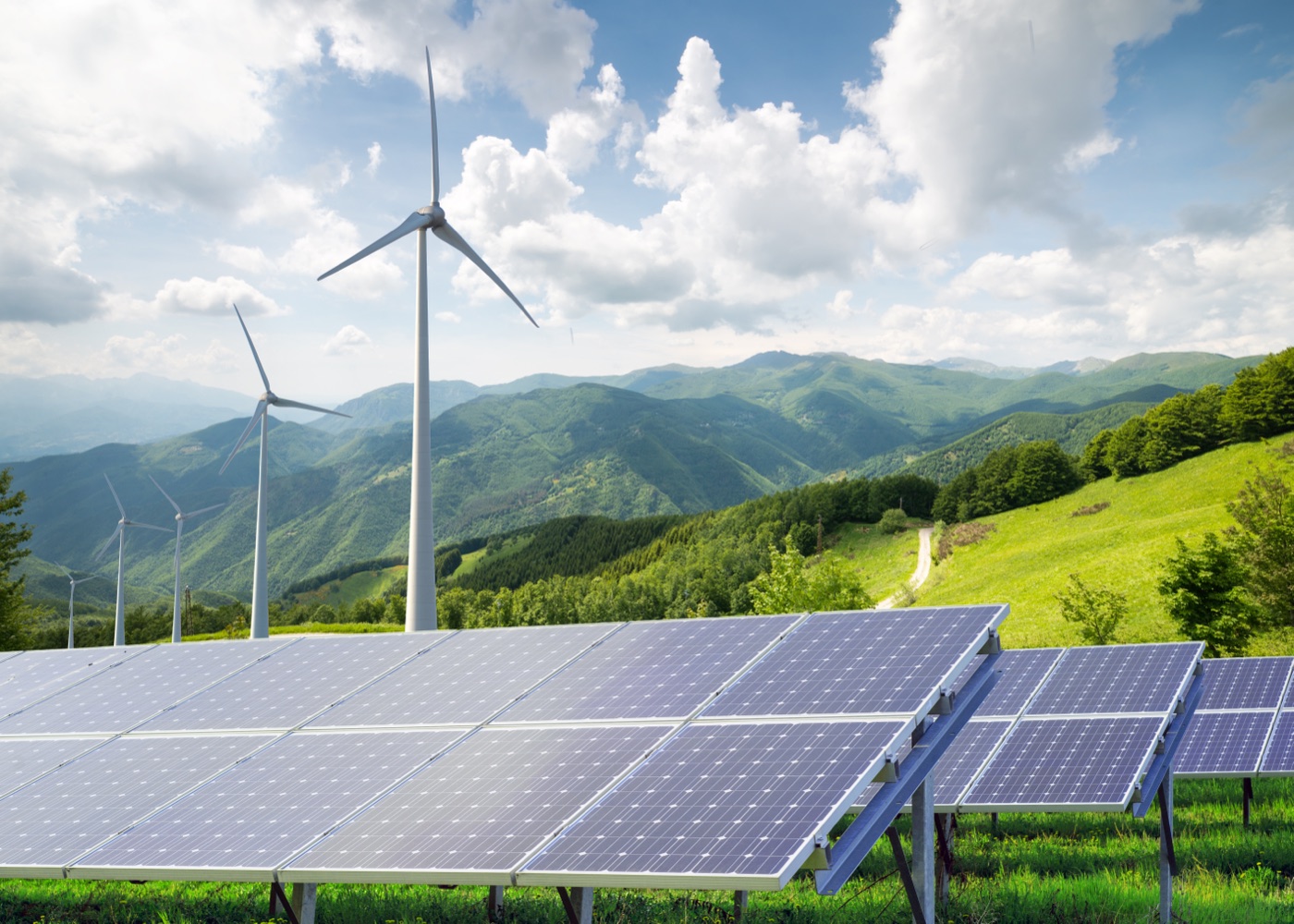 Solar panels and wind turbines with mountain backdrop